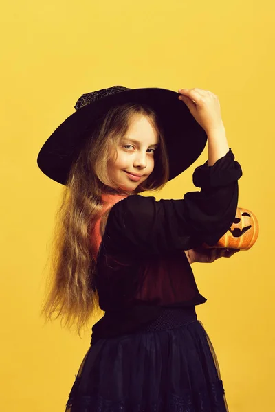 Menina com abóbora laranja esculpida isolada no fundo amarelo quente — Fotografia de Stock