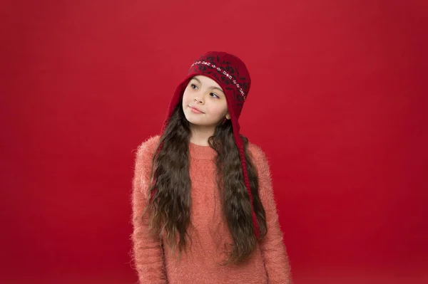 Humor de ensueño. Un niño pequeño usa un sombrero de punto. Mantente caliente. Pequeña niña accesorio de moda de invierno. Pequeño adorable niño pelo largo usar sombrero fondo borgoña. Lindo modelo disfrutar del estilo de invierno. Traje de invierno — Foto de Stock