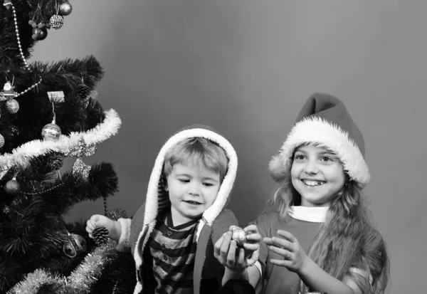 Niños con caras felices juegan con bolas de Navidad en rojo —  Fotos de Stock