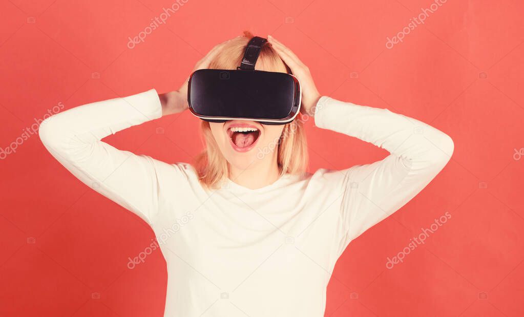 Amazed young woman touching the air during the VR experience. Woman wearing virtual reality goggles. Funny young woman with VR. Futuristic VR.
