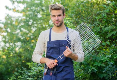 Arka bahçe barbekü partisi. Piknik konsepti. Yemek pişiren yakışıklı adam. Sağlıklı yemek. Tarif ızgarası. Izgara yapmak için farklı yöntemler. Adam ızgara ızgarasını beklesin. Izgara yemek. Açık havada et kızartmak için araçlar