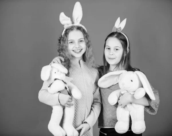 Vrienden kleine meisjes met bunny oren Pasen vieren. Kinderen met bunny speelgoed op blauwe achtergrond. Zusters glimlachend schattige bunny kostuums. Verspreiden van de vreugde en geluk rond. Hoop liefde en vreugdevol leven — Stockfoto