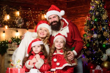 Mutlu bir anı yakalıyorum. Mutlu aile yeni yılı kutluyor. Portre seven aile. Bir sürü Noel hediyesi kutusu var. Mutlu noeller. Anne ve baba çocukları sever. Noel Baba şapkalı küçük çocuklar ve ebeveynler