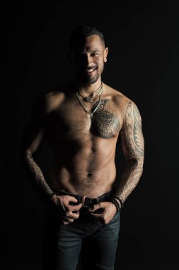 Cilt üzerinde dövme tasarımı ile mutlu bir adam. Sakallı adam gömleksiz fit vücut'la. Kot pantolon moda model toka deri kemer. Sporcu gülümseme ile altı paketi ve AB Fitness Spor ve welness