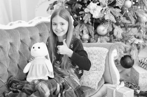 Мені це дуже подобається. Маленькі дівчата до милого кролика на ялинці. Маленька дівчинка тримає кролячу іграшку. Маленька дитина грає з м'якою іграшкою. Маленька дитина щаслива посміхається з подарунком. Краща різдвяна іграшка — стокове фото
