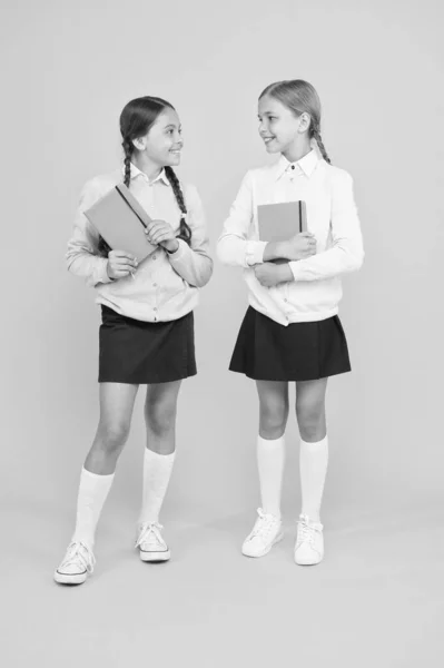 Nos encanta leer. Niños pequeños con libros de lectura sobre fondo amarillo. Las niñas adorables aprenden a leer en la escuela primaria. Lindos alumnos leyendo para aprender información importante — Foto de Stock