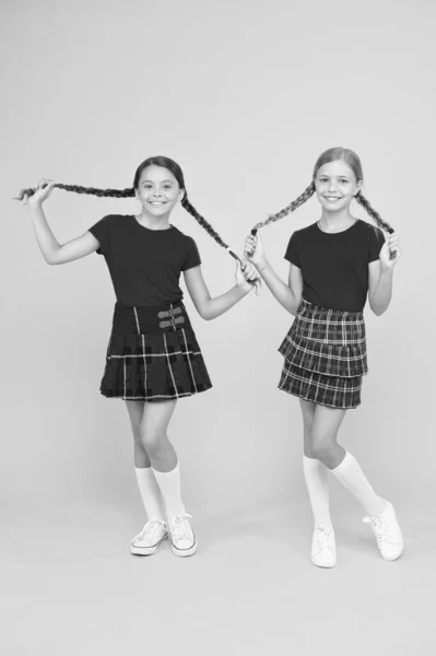 Amigos alegres. Chicas pequeñas y felices con los mismos trajes. Amigos disfrutando de la amistad. Niños juguetones. Felices juntos. Amigos de la escuela divirtiéndose juntos. Lindas niñas sonriendo fondo amarillo —  Fotos de Stock