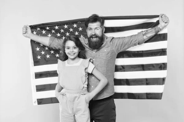 ¿Cómo celebran los americanos el día de la independencia? Familia patriótica alegre y amigable. Vacaciones de día de independencia. La independencia es felicidad. Padre barbudo hipster y linda hijita con bandera de EE.UU. — Foto de Stock