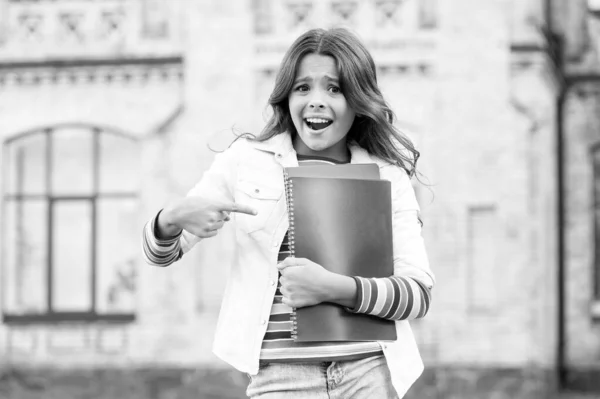 Guarda un po '. Ragazzina felice che punta il dito contro i libri. Bambino piccolo che sorride e indica la copertina dei libri. Usare il gesto puntato per attirare l'attenzione. Estendendo il dito e indicando — Foto Stock