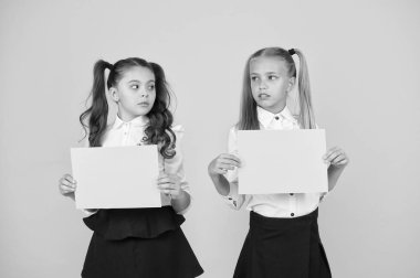 Ev işlerini düşünüyorum. Küçük çocuklar, sınav için boş çarşaflar tutan sarı arka plan üzerinde çalışırlar. Proje çalışması veya araştırma için boş yeşil kağıtları ile küçük kızlar. Kağıt çalışması, kopyalama alanı