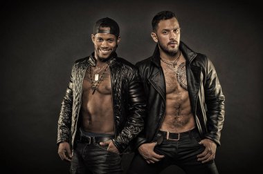 Ceplerinde elele sakallı adam. Afrika adam geriye dönük şapkası. Deri ceketler yan yana duran iki erkek modeli. Seksi organları, motorcularla şehvet ve baştan çıkarma kavramı