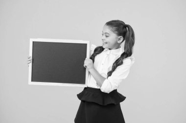 Küçük kız, büyük bir rüya. Küçük çocuk sarı arka plan üzerinde okul reklam için siyah tahta tutan. Mesajın için boş tebeşir tahtası olan küçük bir çocuk. Küçük kız öğrenci kara tahta tutan, kopya alanı