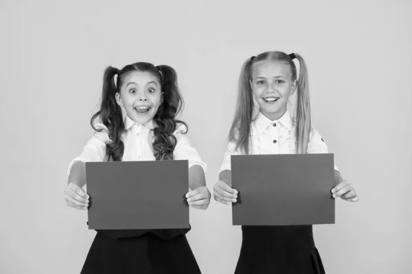 Promote with advertising. Happy small children showing pink paper sheets for advertising on yellow background. Little girl advertising product or event. Advertising and marketing, copy space — Stock Photo, Image