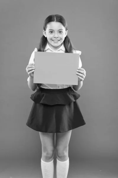 Uma colegial. Menina feliz usar uniforme escolar. De volta ao conceito de escola. Estudante sorrindo aluno mostrar cartaz. Estudante segurar poster espaço de cópia. Anúncio e propaganda. Infância feliz — Fotografia de Stock