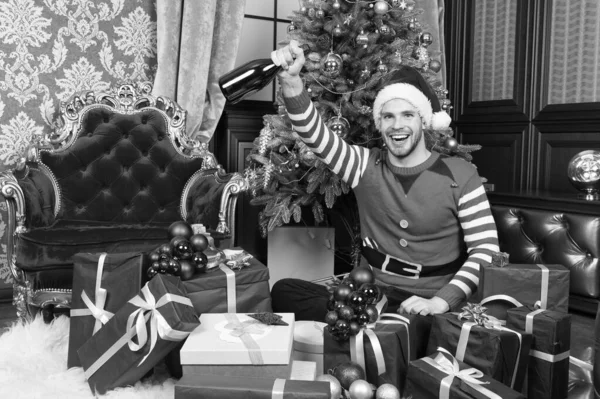 Happy holidays en een welvarende 2019. Man in santa hat greep nieuwe jaar presenteert. Guy viert Nieuwjaar thuis. Gelukkig man met Nieuwjaar geschenkdozen. Prettige kerstdagen en gelukkig Nieuwjaar — Stockfoto