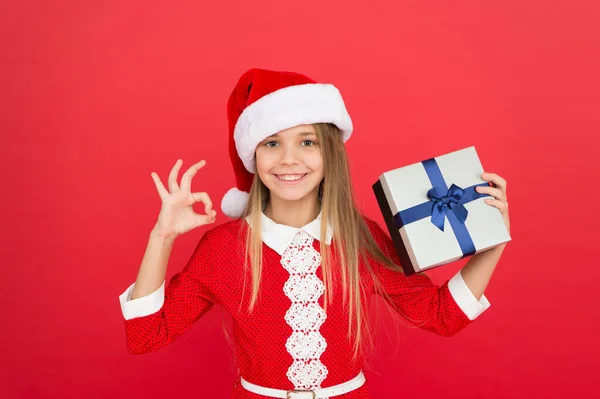 Egy kislány nyitó ajándéka. Újév. Télapó ajándéka. A kislány kapott ajándékot. Ajándék karácsony. Boksz nap. Vidám gyerek piros háttér. Adventi naptár. Lepd meg. Boldog téli ünnepeket! — Stock Fotó