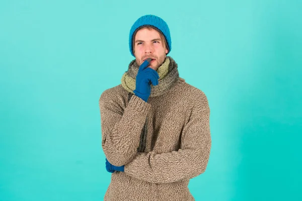 What if. Man handsome unshaven guy wear winter accessories on blue background. Winter season sale. Hipster knitted winter hat scarf and gloves. Emotional expression. Think and decide. Hard decision