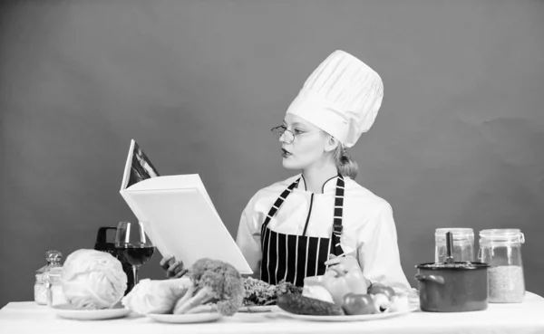 Zamiar gotować coś specjalnego. Ładna kobieta, czytanie książki kucharz w kuchni. Kucharz Pani szuka gotowanie przepis w książkę kucharską. Cute kucharz gosposia przy stole w kuchni — Zdjęcie stockowe