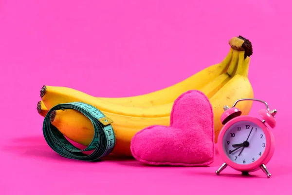 Рулон вимірювальної стрічки та бананів біля серця та будильника — стокове фото