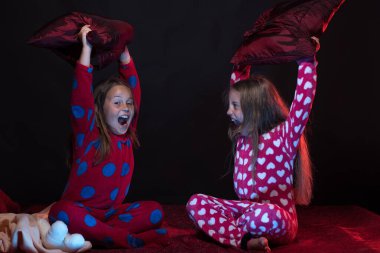 Çocuklar için pijama partisi: kızlar yastıklarla bağırıyor ve kavga ediyor