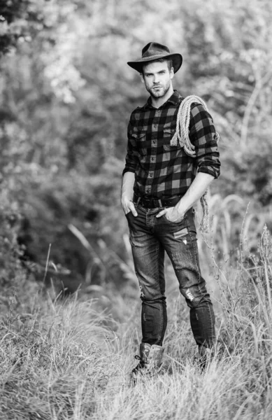 American cowboy. Lasso tied wrapped. Western life. Man cowboy nature background. Man wearing hat hold rope. Ranch owner. attle breeding concept. Cowboy at countryside. Ranch occupations. Lasso tool — Stock Photo, Image