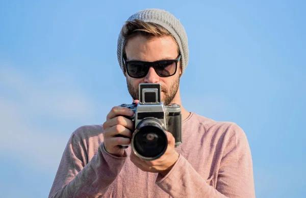 Photojournalist concept. Hipster reporter taking photo. Manual settings. Travel blogger. Professional photographer. Handsome photographer guy retro camera. Guy photographer outdoors sky background — Stock Photo, Image