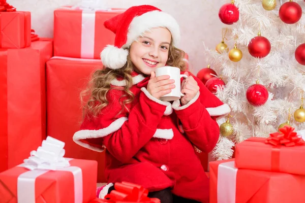 Перфектный способ согреть вас праздничным сезоном. Горячий какао на Рождество. Любимый напиток какао. Девочка маленький милый ребенок держать кружку с горячим напитком во время празднования Рождества. Малыш Санта шляпа насладиться какао напитком — стоковое фото