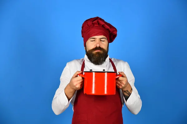 Man met baard houdt keukengerei op blauwe achtergrond. — Stockfoto