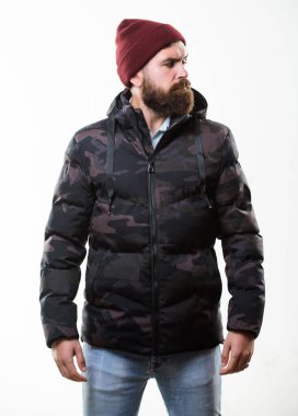 Sakallı adam beyaz arka planda izole edilmiş sıcak kamuflaj desenli ceket giyiyor. Hipster kış modası. Şapka takan ve siyah kışlık ceket giyen adam. Rahat bir kış kıyafeti. Kış stili erkek giyim