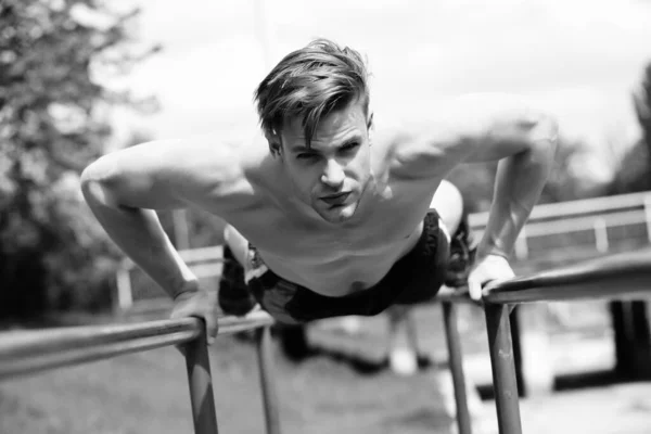 Man with confident face performs on parallel bars — Stock Photo, Image