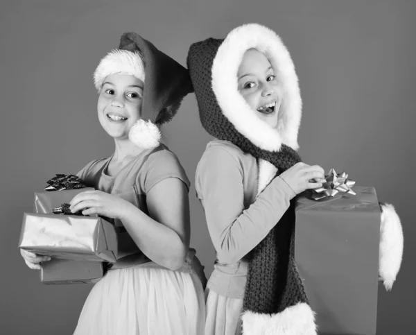 Enfants en chapeaux de Père Noël avec des boîtes cadeaux ouverts cadeaux. — Photo