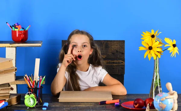 Menina senta-se na mesa com material escolar — Fotografia de Stock