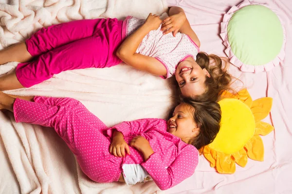 Children with happy faces lie close on pink blanket background. — Stock Photo, Image