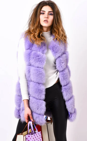 Femme shopping boutique de luxe. Dame tenir des sacs à provisions. Fashionista acheter des vêtements le vendredi noir. Remise vendredi noir. Shopping et cadeaux. Fille maquillage fourrure violet gilet shopping fond blanc — Photo