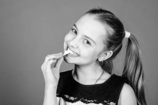 Miúdo faminto. Dente doce incorrigível. Menina sorridente rosto contém doce marshmallows na mão violeta fundo. Conceito dos dentes doces. Miúda com cabelos longos gosta de doces e guloseimas. Calorias e dieta — Fotografia de Stock