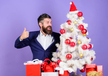 Hazırlık ve kutlama. Harika bir ofis noel partisi nasıl düzenlenir. Kontrol listesi Noel hazırlığı. Sakallı hippi adam Noel ağacının yanında resmi takım elbise giyer. Noel hediyeleri ve dekorasyonlar