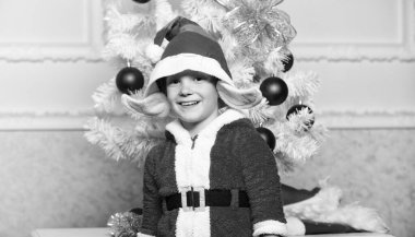 Çocuk çocuk şirin elf büyülü yaratık beyaz suni kulak ve Noel ağacı yakınındaki kırmızı şapka gibi giyinmiş. Noel elf kostümü çocuk için. Elf kostümü ile Noel partisi. Çocuklar için Noel ağacı fikirler