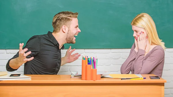 Shocking news. University or college students. Teacher and schoolmaster sitting at desk. Angry man and terrified woman back to school. High school education. Couple studying in classroom