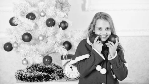 Obtenir enfant impliqué décoration. Fille sourire visage tenir balles ornements fond intérieur blanc. Comment décorer l'arbre de Noël avec un enfant. Laisse le gosse décorer l'arbre de Noël. Partie préférée décoration — Photo