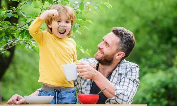 family dinner time. father and son eating outdoor. happy fathers day. Little boy with dad eat cereal. Morning breakfast. Vegetarian diet. healthy food and dieting. Dairy products. Family bonds