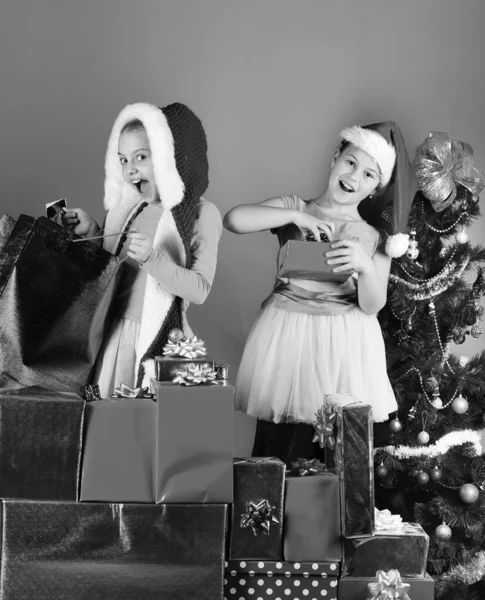 Siostry w kapeluszach Świętego Mikołaja z pudełkami prezentów otwarte prezenty. — Zdjęcie stockowe