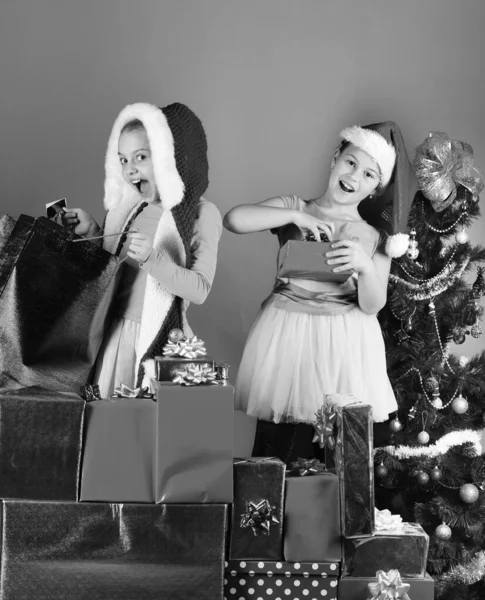 Sisters in Santa Claus hats with gift boxes open presents. — Stock Photo, Image