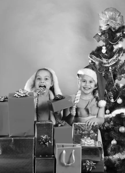 Irmãs em chapéus de Papai Noel ficar atrás de caixas de presente. — Fotografia de Stock
