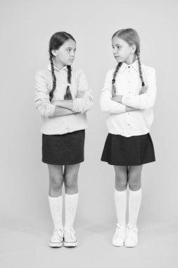 Çocuk modası. Dostlar ve düşmanlar. Eğitim konsepti. Okula dönüyorum. Bilgi günü. Çocukluk psikolojisi. Sarı arka plandaki akıllı küçük kızlar. Okul üniformalı düşmanlar. Yemin ederim.