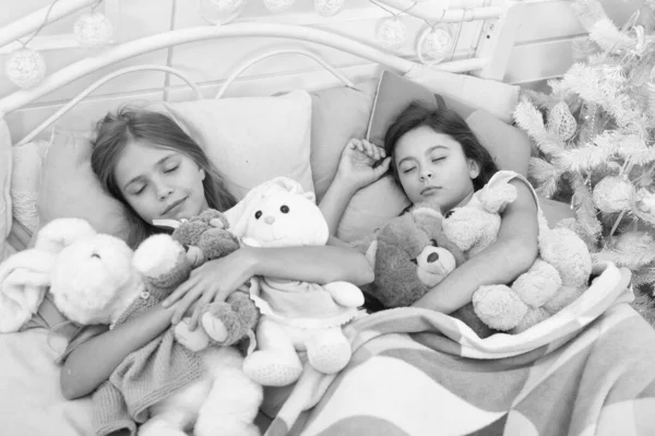 Soñando en color. Niños dormidos. Los niños duermen en el árbol de Navidad. Niñas acostadas en la cama con juguetes. Las chicas lindas se durmieron después de Navidad. Descanso en vacaciones de invierno —  Fotos de Stock