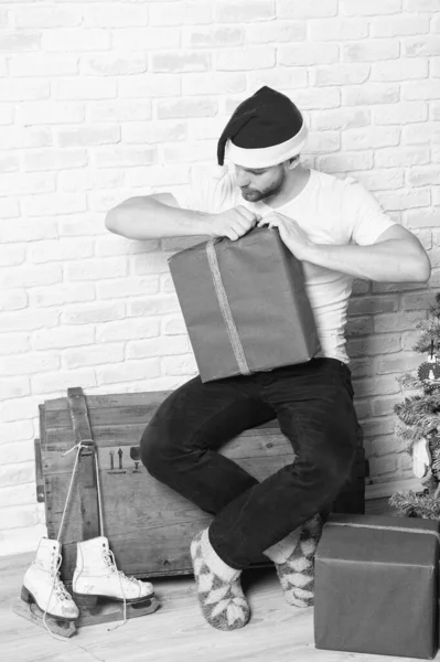 Uomo in cappello Babbo Natale scatola aperta e guardare i pattini — Foto Stock