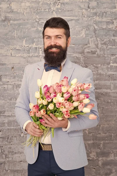 Romantic man with flowers. Romantic gift. Macho getting ready romantic date. Waiting for darling. Tulips for sweetheart. Man well groomed wear tuxedo bow tie hold flowers bouquet. Invite her dating