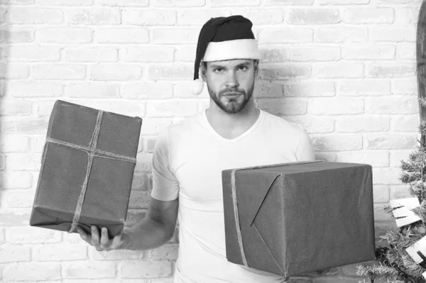 Macho ve vánoční čepice drží zabalené dárky — Stock fotografie