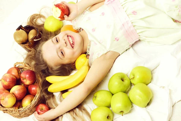 Cute baby girl laying with colorful fruits in basket — Stock Photo, Image