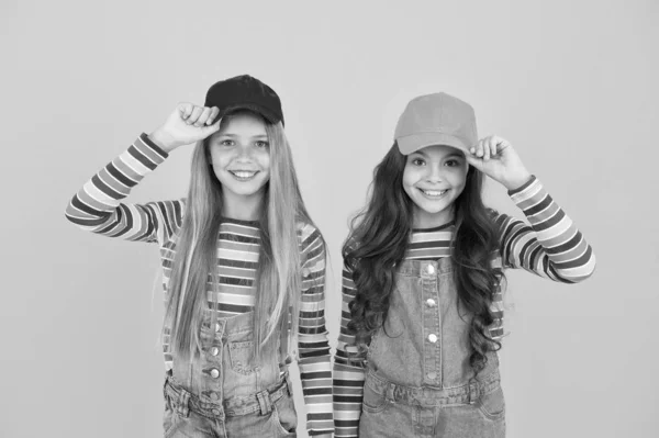 De hipster subcultuur. Gelukkige hippies met baseballcaps op een gele achtergrond. Leuke kleine hipsters glimlachend met modieuze uitstraling. Schattige kinderen in hipsterstijl — Stockfoto